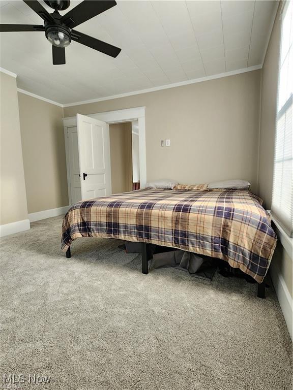 carpeted bedroom with ceiling fan and crown molding