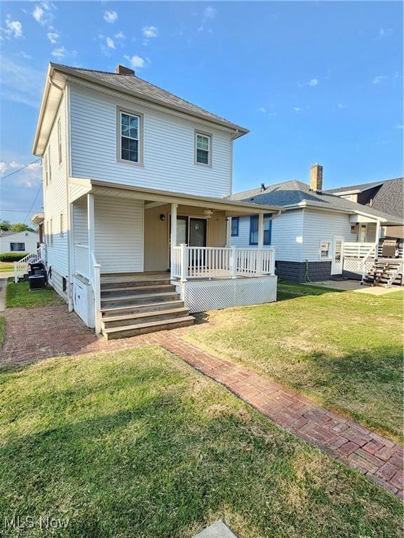 back of property with a lawn and a porch