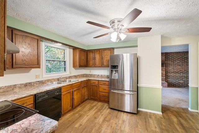 kitchen with light hardwood / wood-style floors, a textured ceiling, dishwasher, sink, and stainless steel fridge