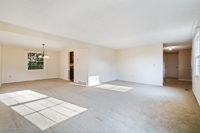 unfurnished room with a chandelier and light colored carpet