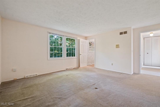 carpeted empty room with a textured ceiling