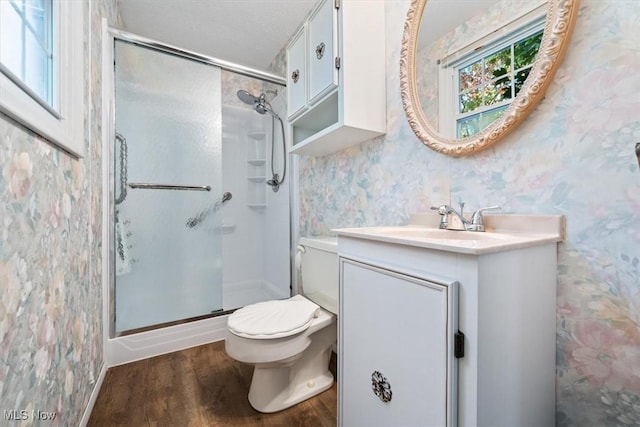 bathroom with hardwood / wood-style floors, an enclosed shower, a textured ceiling, vanity, and toilet