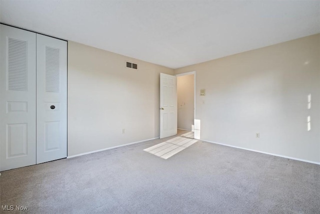 unfurnished bedroom featuring a closet and light colored carpet