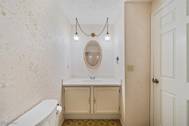 bathroom with vanity, toilet, and a textured ceiling