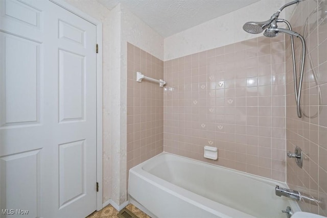 bathroom with tiled shower / bath and a textured ceiling