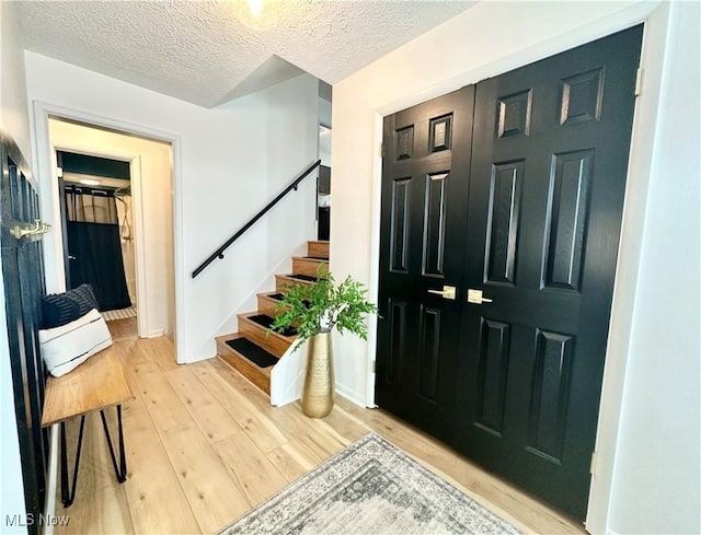 entrance foyer with a textured ceiling and light hardwood / wood-style flooring