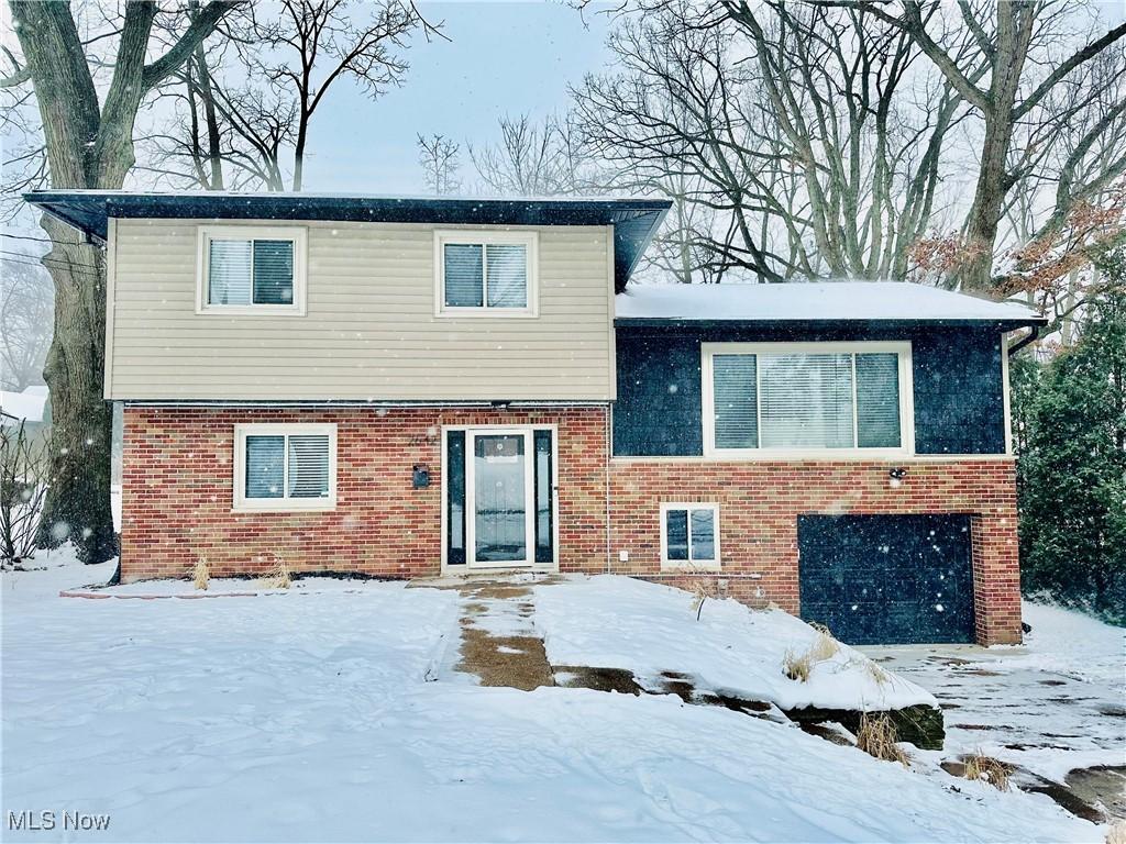 snow covered rear of property featuring a garage