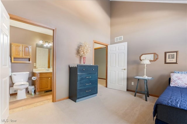 bedroom with light colored carpet, connected bathroom, and sink