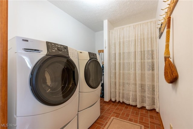 clothes washing area with a textured ceiling and independent washer and dryer