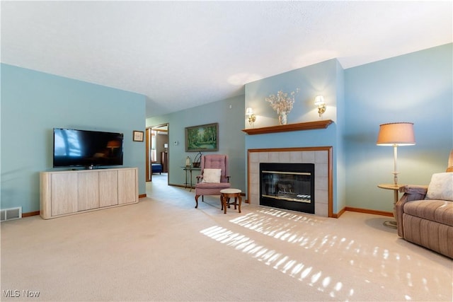 living room with a tile fireplace and carpet flooring