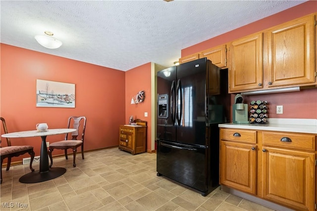 kitchen featuring a textured ceiling and black fridge with ice dispenser