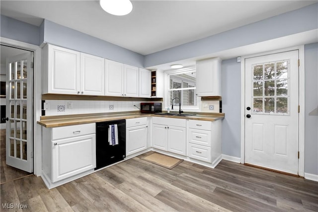 kitchen with decorative backsplash, sink, white cabinetry, and black appliances