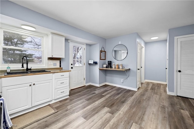 kitchen with hardwood / wood-style flooring, sink, and white cabinets