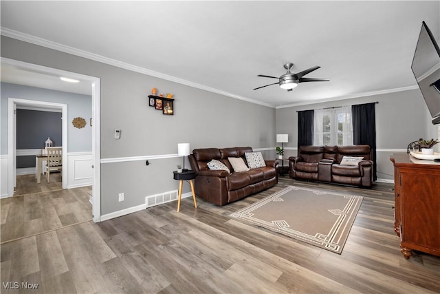 living room with hardwood / wood-style flooring, ceiling fan, and crown molding