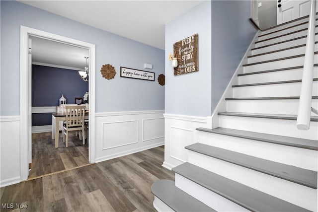 staircase featuring wood-type flooring and a chandelier