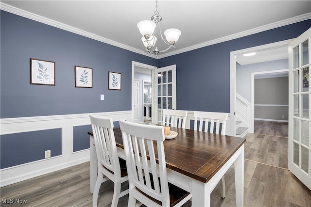 dining room with crown molding, hardwood / wood-style floors, an inviting chandelier, and french doors