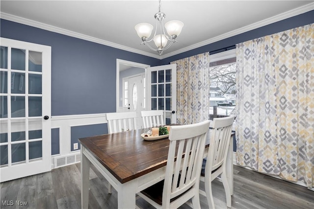 dining space with crown molding, an inviting chandelier, and dark wood-type flooring