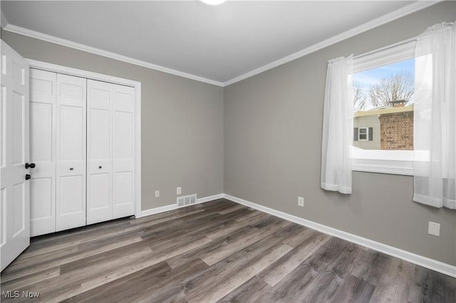 unfurnished bedroom featuring a closet, hardwood / wood-style flooring, and ornamental molding