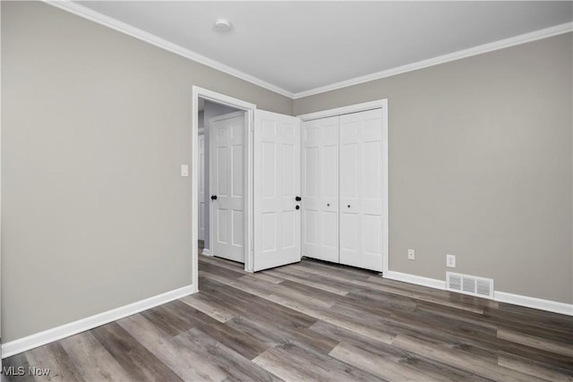 unfurnished bedroom with wood-type flooring, a closet, and ornamental molding