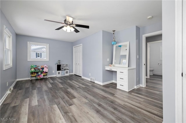 game room with built in desk, ceiling fan, and dark hardwood / wood-style flooring