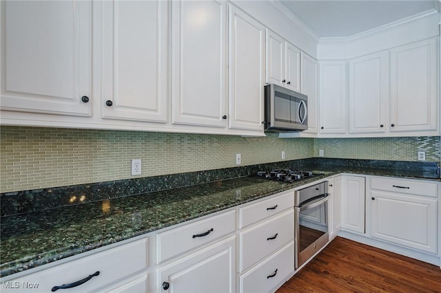 kitchen with backsplash, white cabinets, stainless steel appliances, and dark stone countertops