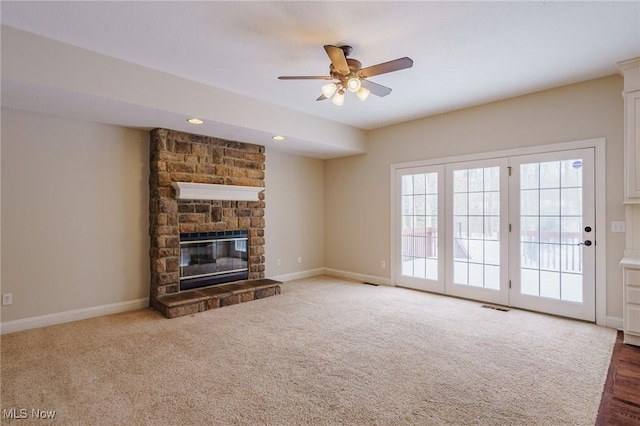 unfurnished living room with ceiling fan, dark colored carpet, and a fireplace