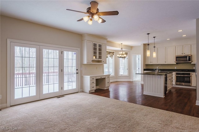 kitchen featuring white cabinetry, hanging light fixtures, a center island with sink, and stainless steel appliances