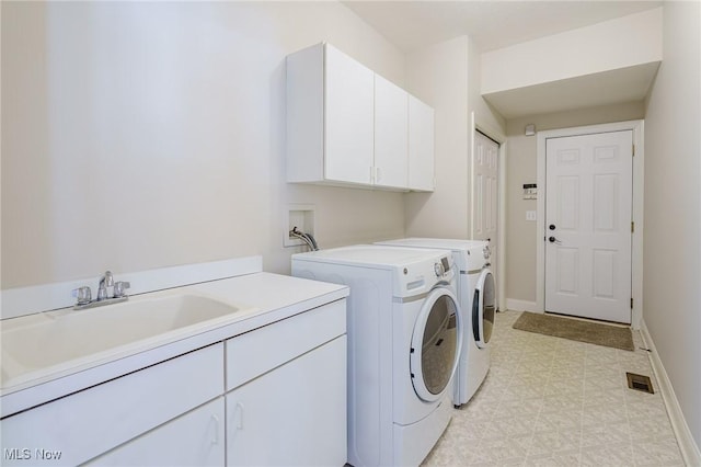 clothes washing area featuring sink, cabinets, and washing machine and clothes dryer