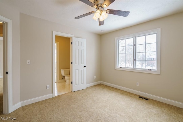 unfurnished bedroom with ceiling fan, ensuite bathroom, and light carpet