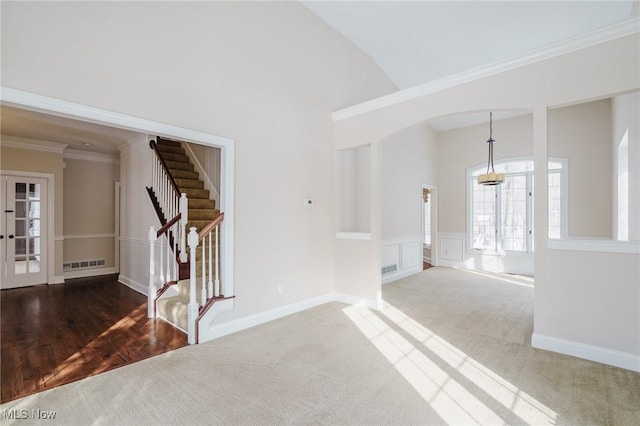 carpeted foyer featuring lofted ceiling, crown molding, and french doors