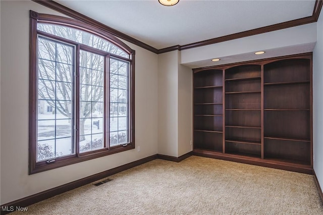 carpeted empty room with built in shelves and ornamental molding