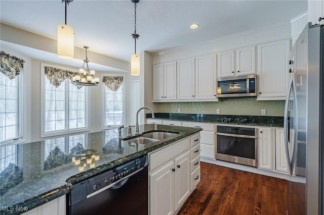 kitchen featuring black appliances, hanging light fixtures, white cabinets, sink, and dark stone counters