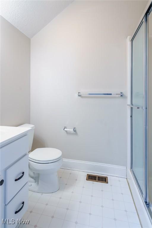 bathroom with vanity, toilet, a textured ceiling, and a shower with shower door