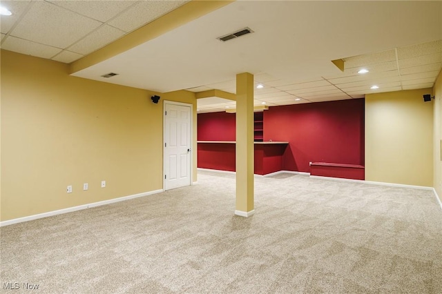 basement featuring a drop ceiling and carpet