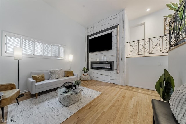 living room with wood-type flooring, vaulted ceiling, and a fireplace