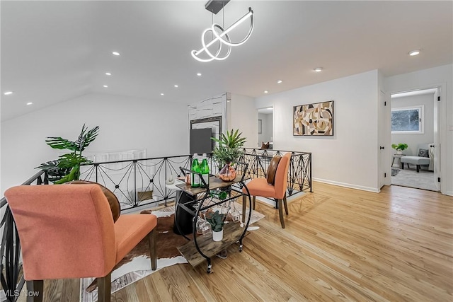 living area featuring lofted ceiling, a notable chandelier, and light wood-type flooring