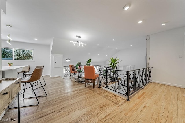 interior space with an inviting chandelier, lofted ceiling, and light wood-type flooring