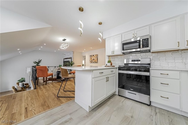 kitchen featuring appliances with stainless steel finishes, white cabinetry, hanging light fixtures, tasteful backsplash, and kitchen peninsula