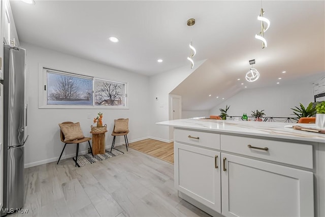 kitchen with light stone counters, decorative light fixtures, light hardwood / wood-style flooring, stainless steel fridge, and white cabinets