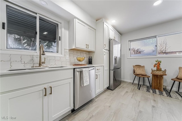 kitchen with tasteful backsplash, appliances with stainless steel finishes, sink, and white cabinets