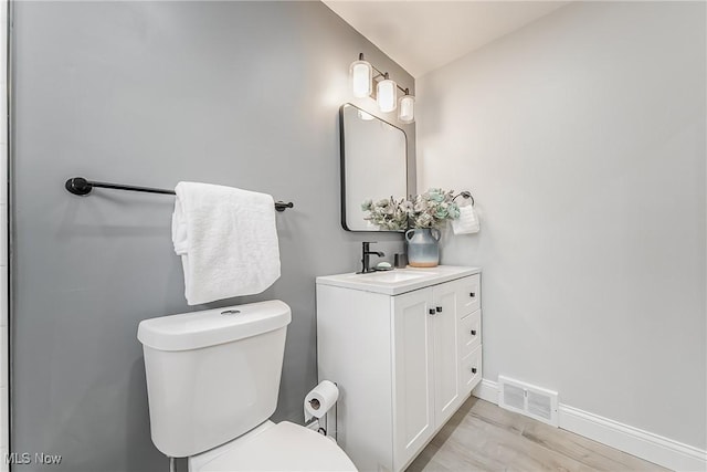 bathroom with vanity, toilet, vaulted ceiling, and hardwood / wood-style floors