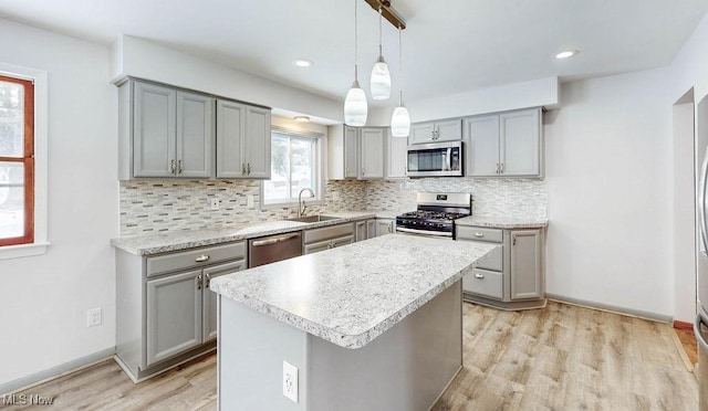 kitchen with sink, a kitchen island, pendant lighting, stainless steel appliances, and gray cabinets