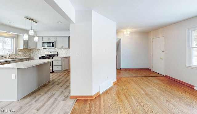 kitchen with pendant lighting, appliances with stainless steel finishes, gray cabinets, and a center island