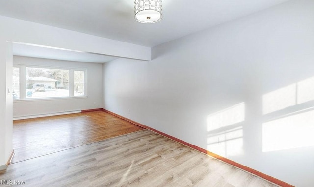 unfurnished room with a baseboard radiator and light hardwood / wood-style floors