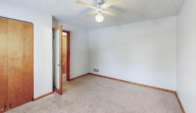 unfurnished bedroom featuring a textured ceiling, light colored carpet, a closet, and ceiling fan