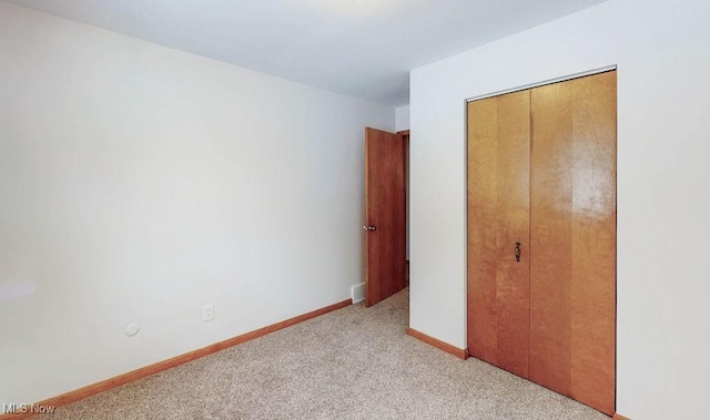 unfurnished bedroom featuring light carpet and a closet