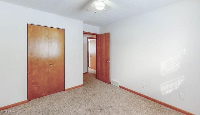 unfurnished bedroom featuring a closet, ceiling fan, and light colored carpet