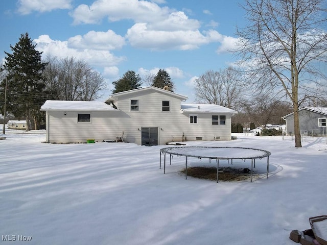 snow covered house featuring a trampoline