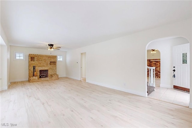 unfurnished living room with a brick fireplace, light hardwood / wood-style flooring, and ceiling fan