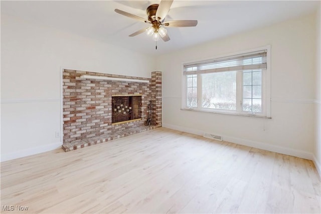 unfurnished living room featuring a fireplace, light hardwood / wood-style floors, and ceiling fan